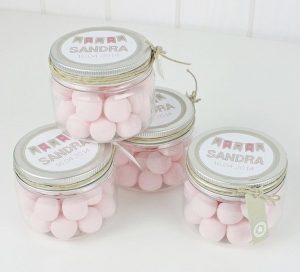 4 frascos transparentes llenos de dulces rosados.