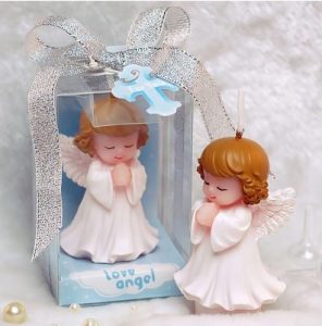 Velas aromáticas en forma de niños pequeños con alas y túnica blanca como recordatorios de bautizo