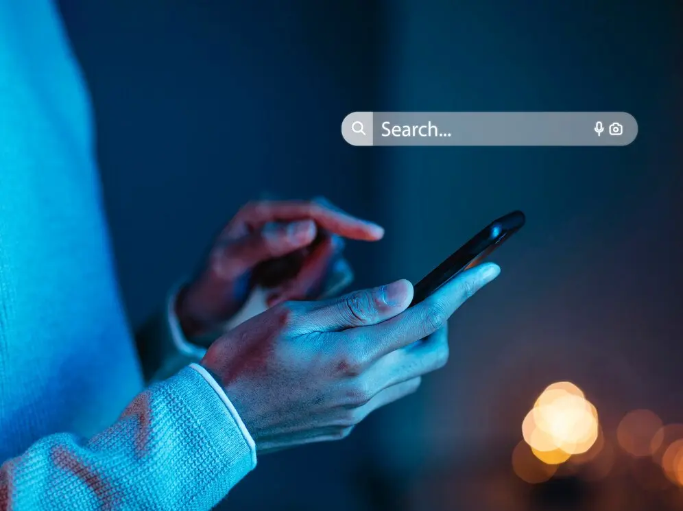 Persona utilizando la inteligencia artificial en un dispositivo móvil, explorando las diferencias con Google