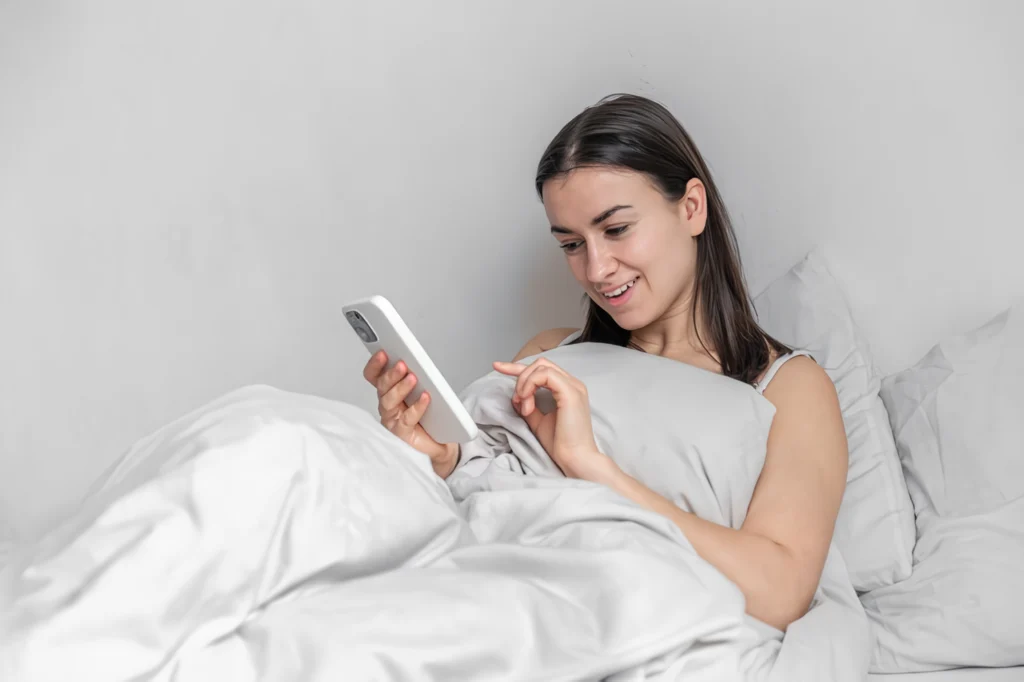 chica en su cama leyendo de su celular