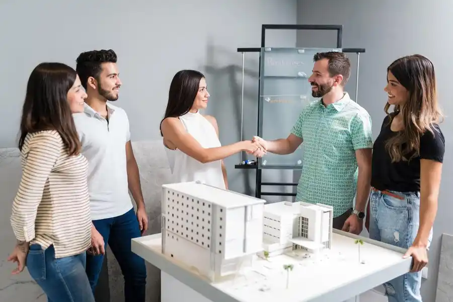 Agente inmobiliario siendo intermediario entre clientes que vana  realizar una compra de una propiedad en agencia inmobiliaria