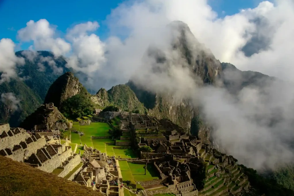 Vista panorámica de Machu Picchu, una de las maravillas del mundo, rodeada de nubes y montañas, destacando el impacto del turismo transformador al conectar a los viajeros con el patrimonio cultural y natural de Perú.