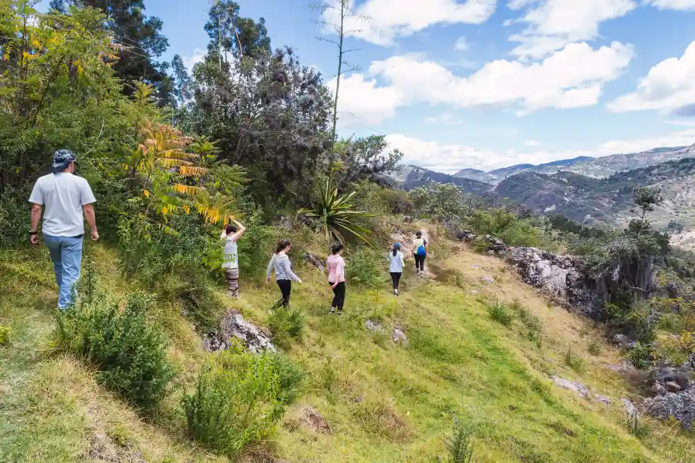 Grupo de personas disfrutando de una caminata por un paisaje montañoso, representando la actividad física y la conexión con la naturaleza como parte del turismo transformador.