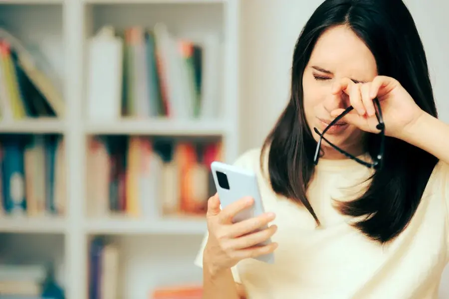 Chica raspándose el ojo por ver su celular