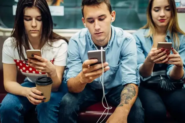 tres chicos viendo su celular demostrando la dependencia hacia la electricidad que tienen