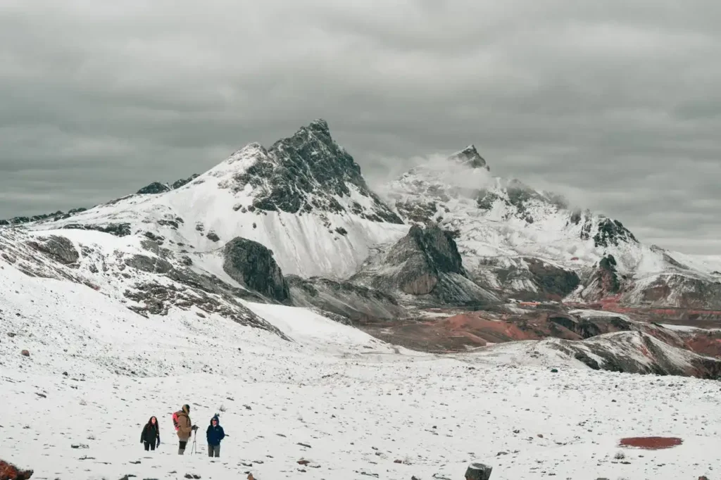 Grupo de viajeros realizando trekking en un paisaje de montaña nevada, destacando el turismo transformador como una experiencia de conexión con la naturaleza y el entorno."