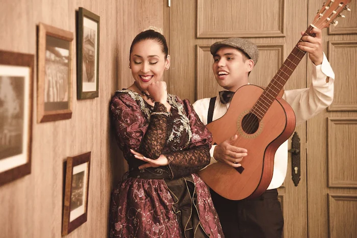 un chico tocando la guitarra criolla a una mujer