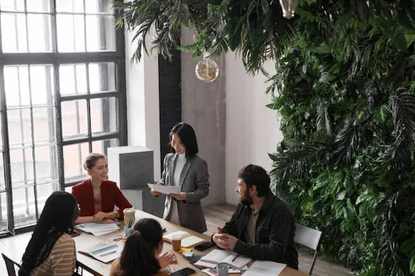 Equipo de trabajo colaborando en oficina sostenible con diseño biofílico y jardín vertical